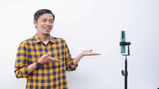 Asian young man recording video content, dancing on smartphone camera at studio. Positive millennial filming for social media, using mobile device.