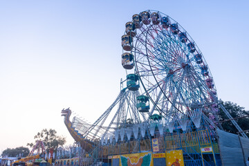 Ferris Wheel or Joint wheel ride running under blue sky on fair ground during the annual dussehra fair.