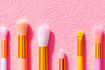 Fototapeta premium An aesthetic flatlay of a set of organized makeup brushes neatly arranged on a textured pink background perfect for beauty and cosmetics themes