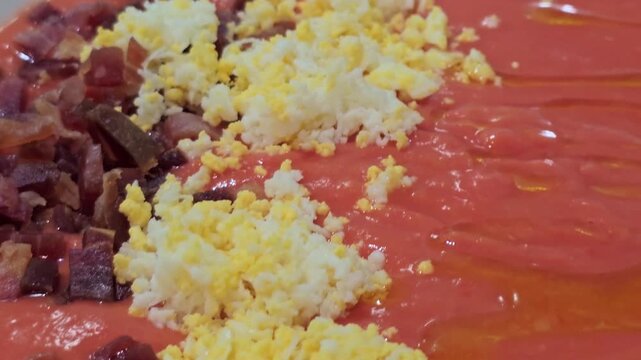 Salmorejo, a traditional Spanish cold soup, is garnished with chopped hard boiled egg and Iberian ham
