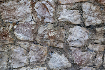 Rock wall texture in gray and brown tones, rough and weathered surface, perfect as a rustic background or architectural detail.
