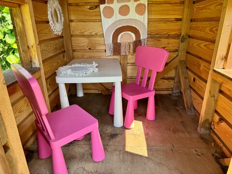 A wooden playhouse for children featuring a fully furnished interior, inspire imaginative play - Powered by Adobe