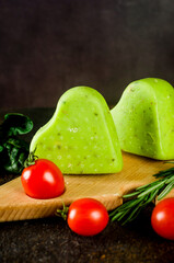 handmade cheese head with pesto in the shape of a heart on a cutting board