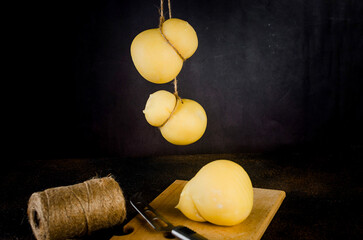 farmhouse homemade caciocavallo cheese wheels hanging on dark background
