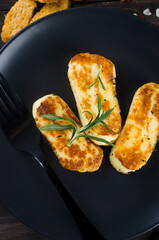 Pieces of fried halloumi on a plate and tomatoes. Balanced and healthy food.