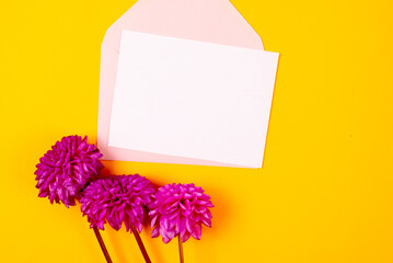 Blank greeting card mockup with pink envelope and purple dahlias flowers