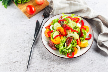 vegetable salad of fresh tomatoes, cucumbers, onions, lettuce on white plate.