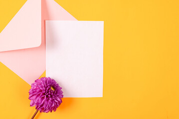 Blank greeting card mockup with pink envelope and purple dahlias flowers