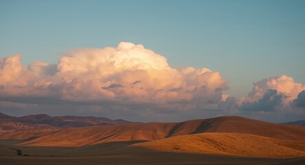 Naklejka premium Rolling Hills under a PeachColored Sky A Serene Landscape at Sunset, Russia