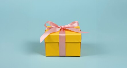 Yellow gift box with pink ribbon on a blue background, minimalistic composition.