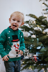 Little boy sticking out tongue at Christmas tree playful expression