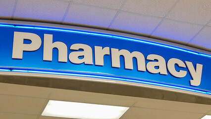 A vibrant pharmacy sign glows prominently against a clean, bright interior.