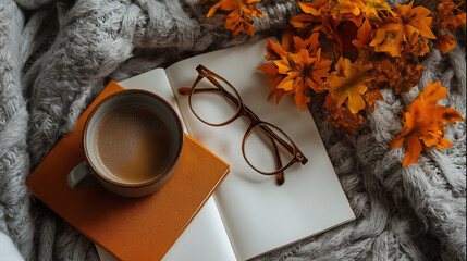 Autumn flatlay with orange leaves, notebook, coffee, and glasses arranged aesthetically, creating warm cozy seasonal scene with soft textures.