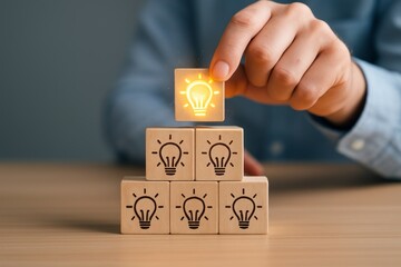 Hand stacking wooden cubes with lightbulb icons, top cube glowing to represent creative idea and innovation in business strategy