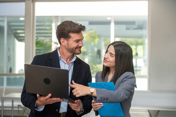 Business colleagues collaborating on laptop in modern office
