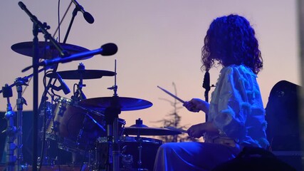 Silhouette of a female drummer playing drums against the background of the sunset sky, slow motion - Powered by Adobe
