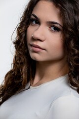 Naklejka premium A captivating portrait of a young woman with curly hair, set in soft lighting enhancing her charm