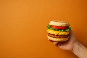 Classic burger with sesame bun and mug of beer on vibrant orange background