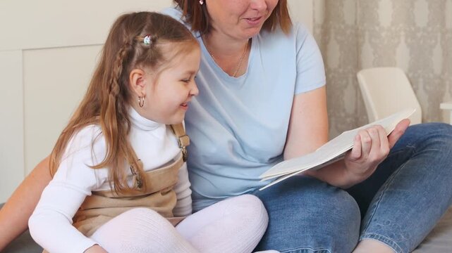 Mother reads a children's book to her daughter during a cozy home session. Learning and bonding through early childhood reading. Close up.