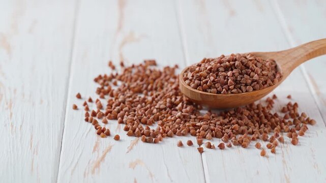 Organic buckwheat in a wooden spoon on a white kitchen table.
buckwheat in a wooden spoon on a light kitchen table.
