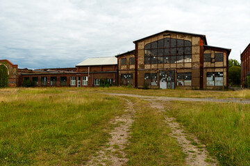 Eine alte Industriehalle mit großen Fensterfronten und verwitterter Fassade steht verlassen auf...