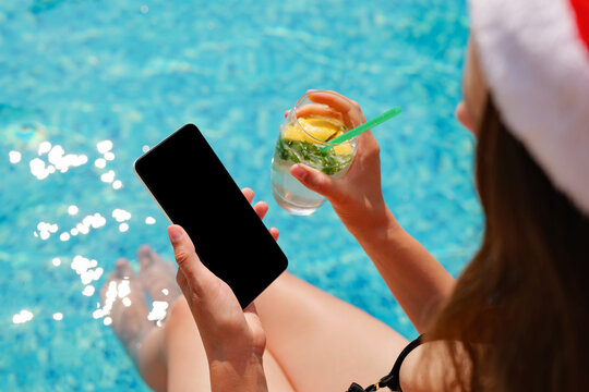 Relaxing by the pool, someone sips a cool beverage and checks their phone on a warm, sunny afternoon