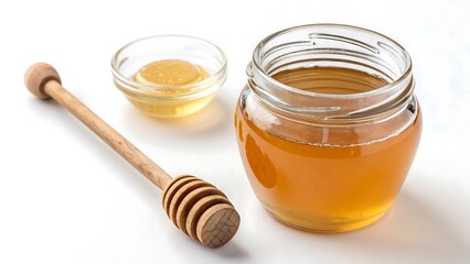 Golden honey in a glass jar with a wooden dipper and small bowl on a white background