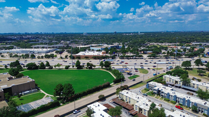 Fototapeta premium Midtown Dallas skyline background from low rise flat roofed apartment complex buildings, green space, busy retail and business corridor along US-75 expressway dense traffic in Richardson, Texas
