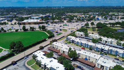 Urban low rise flat roofed apartment complex buildings, green space, and busy retail and business...