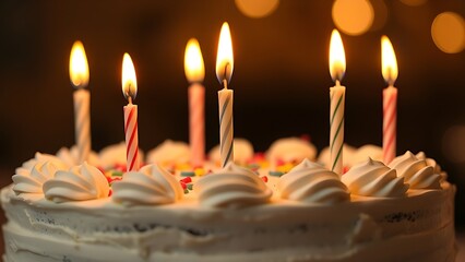 Close-up of a birthday cake with lit candles, glowing warmly in soft diffused light.
