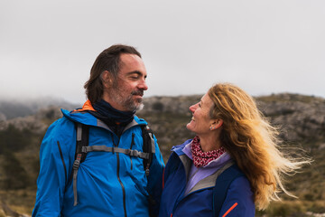 Middle aged couple looking at each other with affection while hiking. Concept of connection, outdoor lifestyle, active aging.