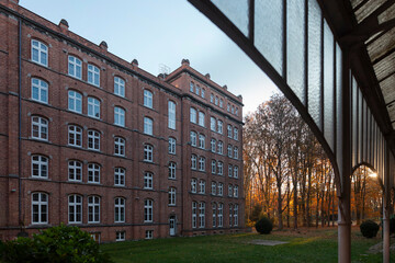 Historic brick institutional buildings viewed from covered walkway showing autumn trees and traditional architecture