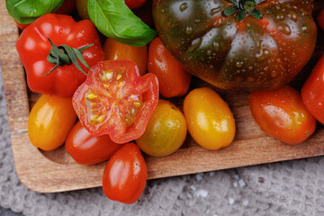Macro view of heirloom tomatoes and fresh basil with water droplets on a rustic tray, perfect for clean eating and vegan food visuals