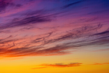 Vibrant Orange, Pink, Violet, and Yellow Sunset Sky with Clouds at Dusk.