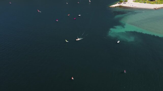 Lake Garda rescue boat approaching fallen windsurfer near Torbole beach, aerial top view