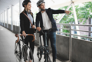 Commuting to work with bicycle. Businessman businesswoman cycling to office in downtown district....