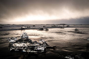Crystal-clear chunks of ice lying on Diamond Beach black sand of Iceland&rsquo;s coast near J&ouml;kuls&aacute;rl&oacute;n, creating a striking contrast in color and texture