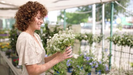 Woman smelling white flowers in a garden center - Powered by Adobe