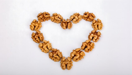 Fototapeta premium Walnut halves arranged in a heart shape on a clean white surface, healthy lifestyle concept
