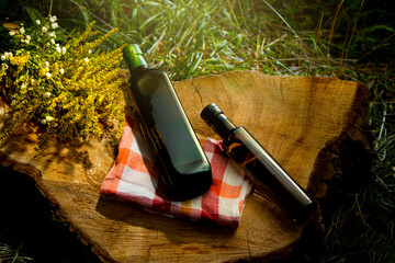 Two dark glass bottles with caps resting on a cut tree trunk. Natural, healthy, organic food products. Herbal medicine or apothecary in harmony with nature. Glass bottles for olive oil.