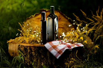 Dark glass bottle. Tinted glass bottle for olive oil and other oils, surrounded by nature. Natural, organic food. Natural food products in a bottle. Herbal medicine.