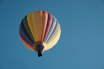Obraz premium Colorful hot air balloon in flight against the sky. Hot air balloons are aircraft that obtain their lift by heating a large envelope of air above ambient temperature. Real photography, not AI.