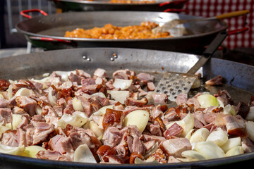 Cooking pork knuckle with onions in large outdoor pan