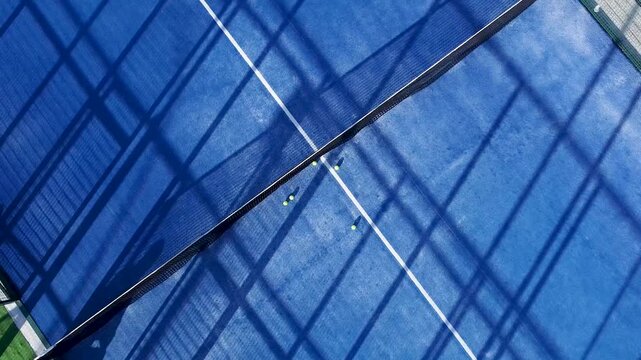 A drone flies over a beautiful and clean padel court with yellow balls on a sunny day summer recreation concept