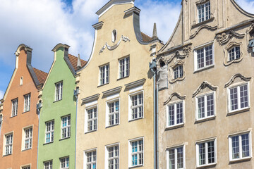 Gdansk, a city on the Baltic coast of northern Poland, Europe. Colorful historical buildings with unique architectural details against a blue sky and white clouds in a quaint European town.