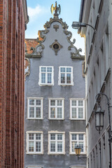 Gdansk, a city on the Baltic coast of northern Poland, Europe. Detailed facade with intricate architecture featuring white-framed windows and ornate embellishments, captured between buildings.