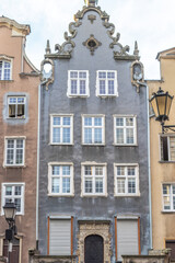 Gdansk, a city on the Baltic coast of northern Poland, Europe. Architectural facade of a tall building with gray walls and several white-framed windows, showcasing old-world charm and intricate design