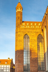 Fototapeta premium St. Mary's Church in Gdansk, a city on the Baltic coast of northern Poland, Europe. Architectural marvel: Towering brick building with intricate windows against a blue sky.