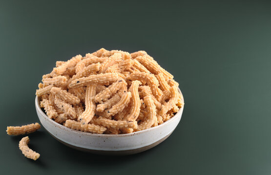 Indian snack murukku made from rice flour and spices on green background. Top view. Indian food.