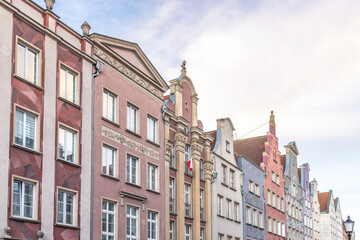 Fototapeta premium Gdansk, a city on the Baltic coast of northern Poland, Europe. Colorful historic buildings stand side-by-side in a European cityscape showcasing architectural diversity under a partly cloudy sky.